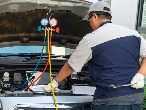 Technician servicing a vehicle air conditioning system in the workshop
