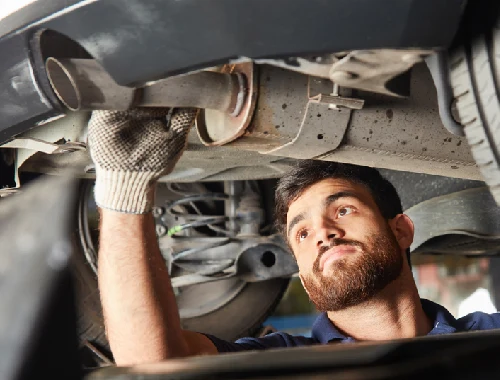 Mechanic working on exhaust system and emissions-related components