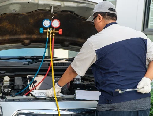 Technician servicing a vehicle air conditioning system in the workshop