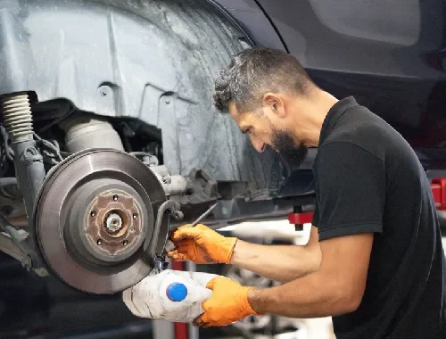 Brake technician checking braking components during a vehicle repair