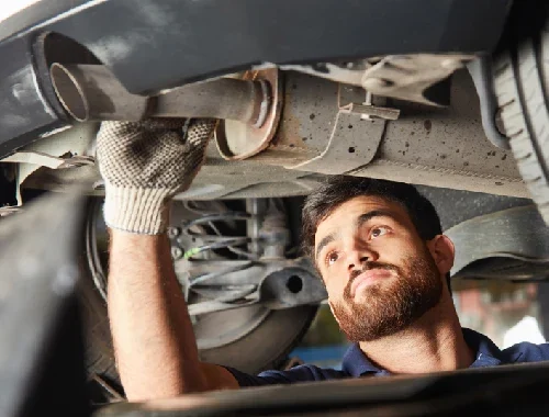 Mechanic working on exhaust system and emissions-related components