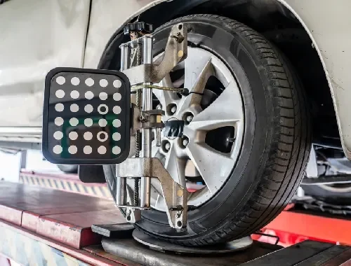 Mechanic checking tyres and wheel alignment equipment on a vehicle